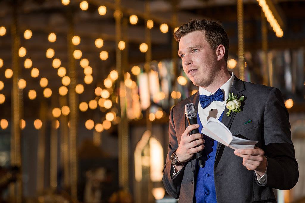 Best man giving a toast under string lights